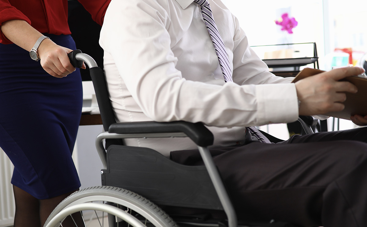 A man being pushed in a wheelchair at work