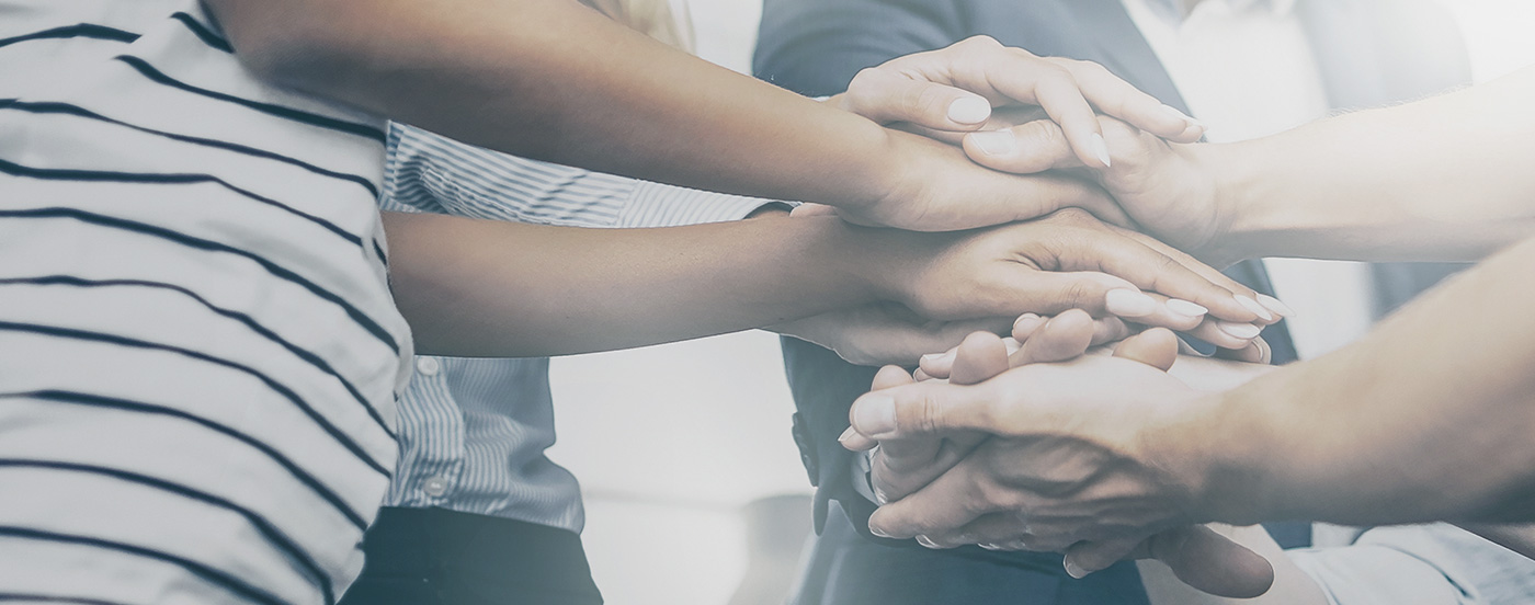 Image of a group of people placing their hands together