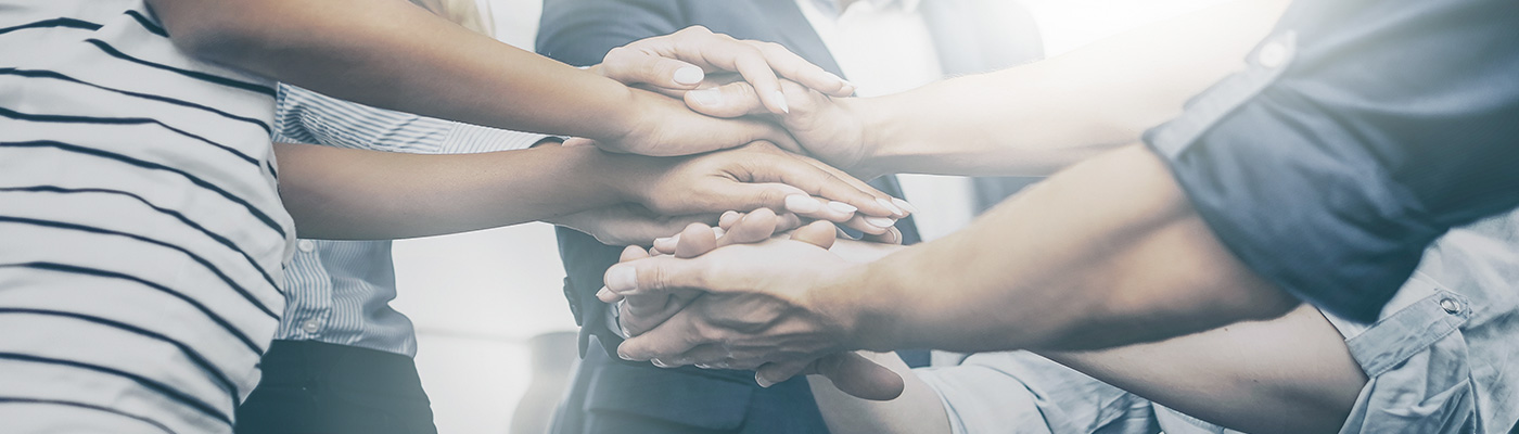 Image of a group of people placing their hands together