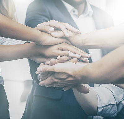 Image of a group of people placing their hands together